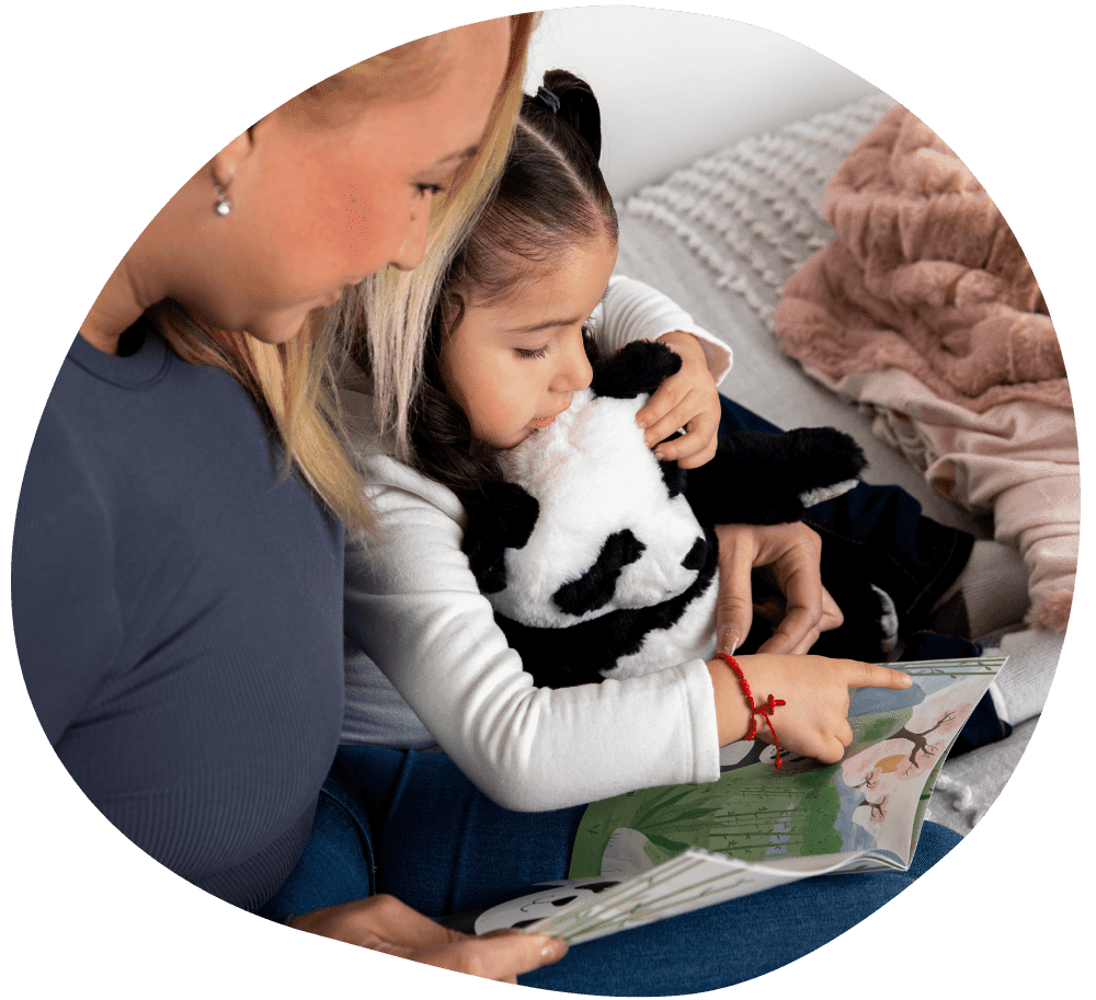 Mother reading story book while holding daughter and Pause with Panda on lap